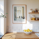 a kitchen counter with a bowl of lemons, a framed poster of a classical architectural scene, and a shelf with various jars and containers.