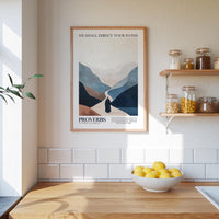 a kitchen counter with a bowl of lemons, a framed poster of a mountain landscape, and a shelf with jars and containers.