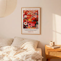 a bedroom setting with a framed poster of a colorful floral design hanging on the wall above a bed with striped pillows.