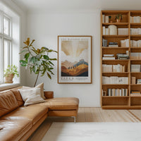 a cozy living room with a large bookshelf filled with books, a comfortable leather sofa, and a framed poster of a landscape on the wall.