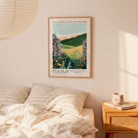 a bedroom scene with a framed poster of a pastoral landscape hanging on the wall above a bed with striped pillows.