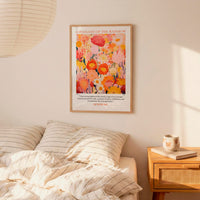 a bedroom setting with a bed, a nightstand, and a framed poster of a colorful floral design hanging on the wall above the bed.