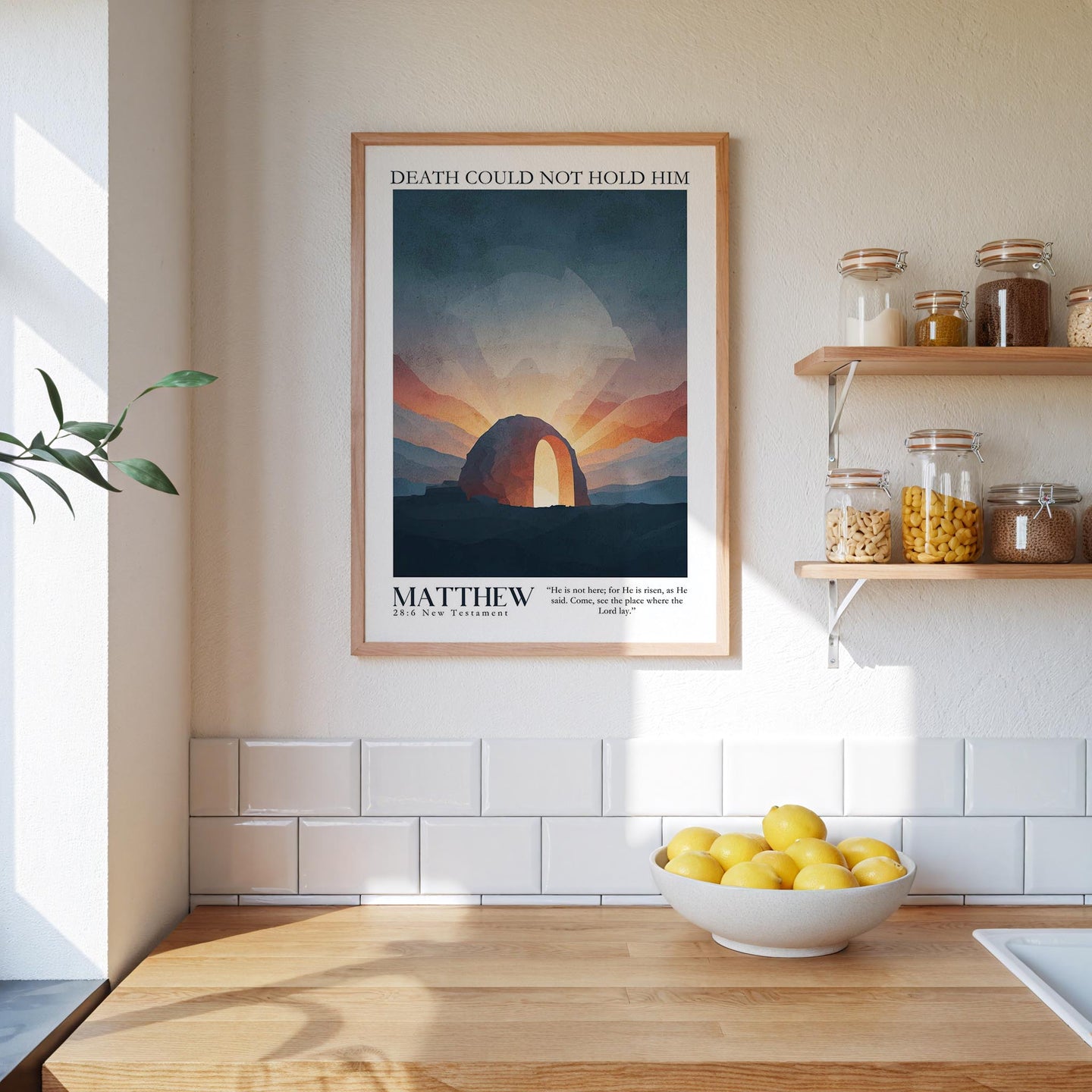 a kitchen scene with a framed poster of a sunset landscape hanging on the wall above a wooden countertop with a bowl of lemons.