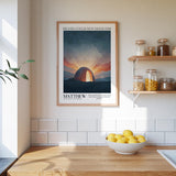 a kitchen scene with a framed poster of a sunset landscape hanging on the wall above a wooden countertop with a bowl of lemons.