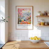 a kitchen scene with a framed poster of a colorful illustration of a cityscape, a bowl of lemons, and shelves with various jars and containers.
