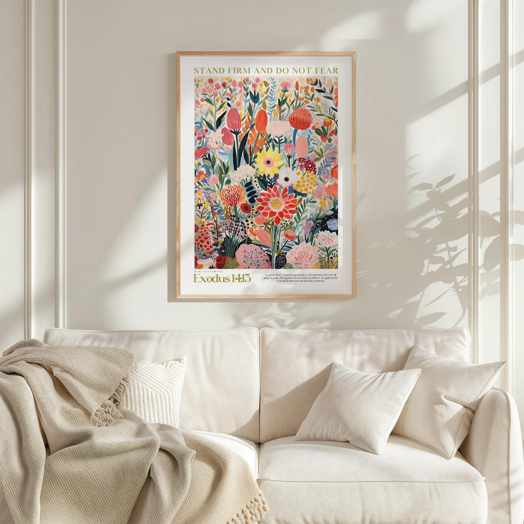 a vibrant, colorful poster of flowers hanging on a wall above a white couch with a blanket draped over it.