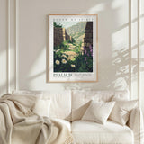 a framed poster of a scenic landscape with a stone wall and flowers hanging above a white couch with a blanket draped over it.
