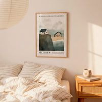 a bedroom setting with a framed poster of a coastal scene hanging on the wall above a bed with striped bedding.
