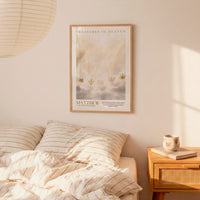 a bedroom scene with a framed poster of a serene landscape hanging on the wall above a bed with striped bedding.