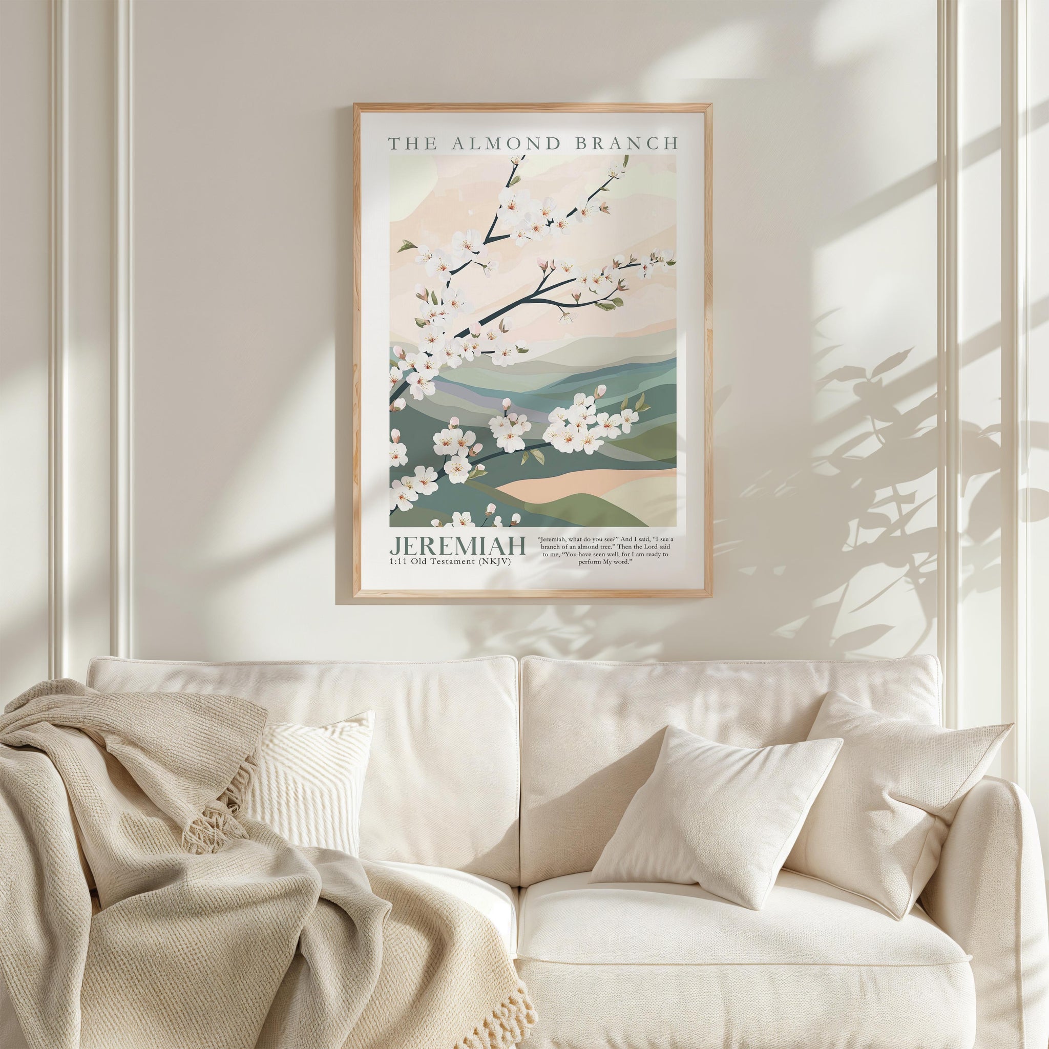 a framed poster of a floral design hanging on a wall above a white sofa with a blanket draped over it.