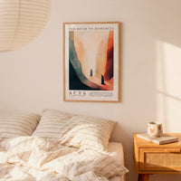a bedroom setting with a framed poster of a desert landscape hanging on the wall above a bed with striped bedding.