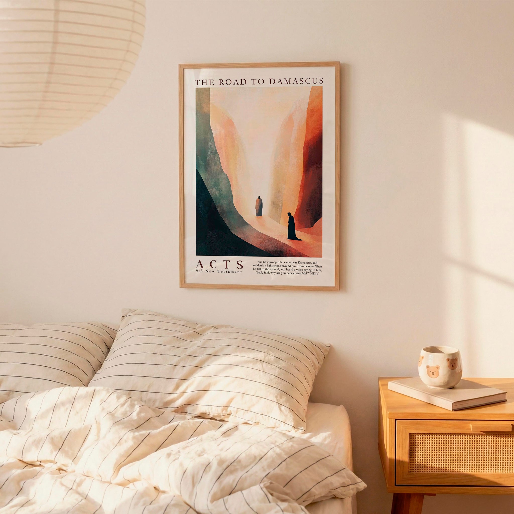a bedroom setting with a framed poster of a desert landscape hanging on the wall above a bed with striped bedding.