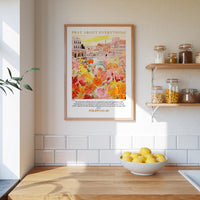 a kitchen scene with a framed poster of a colorful garden hanging on the wall above a wooden countertop with a bowl of lemons.
