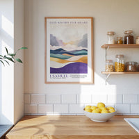A framed poster of a mountain landscape hangs on a wall above a wooden countertop with a bowl of lemons.