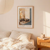 a bedroom setting with a framed poster of a group of people on the wall above a bed with striped bedding.