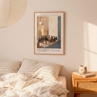 a bedroom setting with a framed poster of a group of people on the wall above a bed with striped bedding.