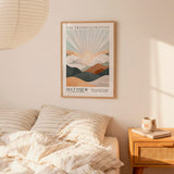 a bedroom scene with a framed poster of a mountain landscape hanging on the wall above a bed with striped bedding.