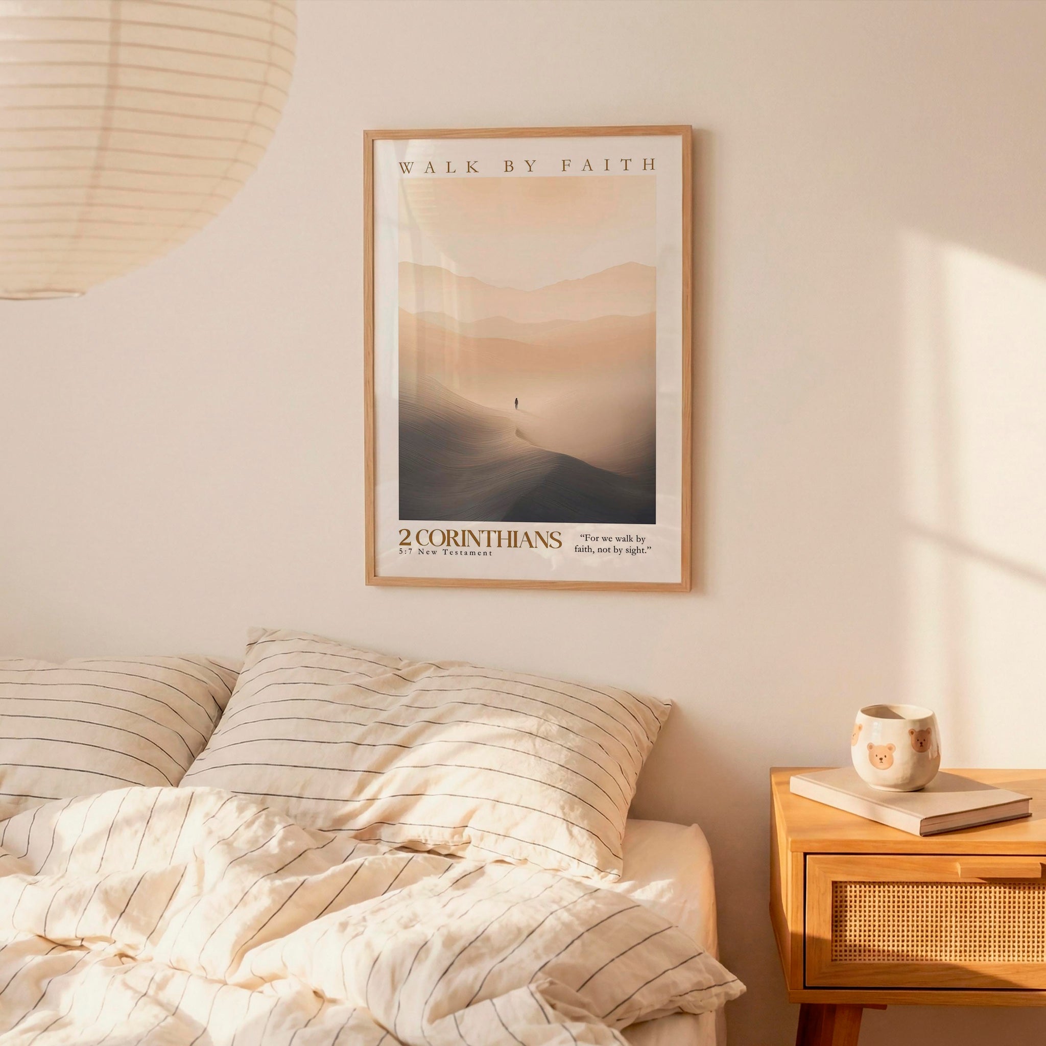a bedroom scene with a framed poster of a person walking on a mountain, a bed with striped bedding, and a wooden nightstand with a coffee mug and a book.