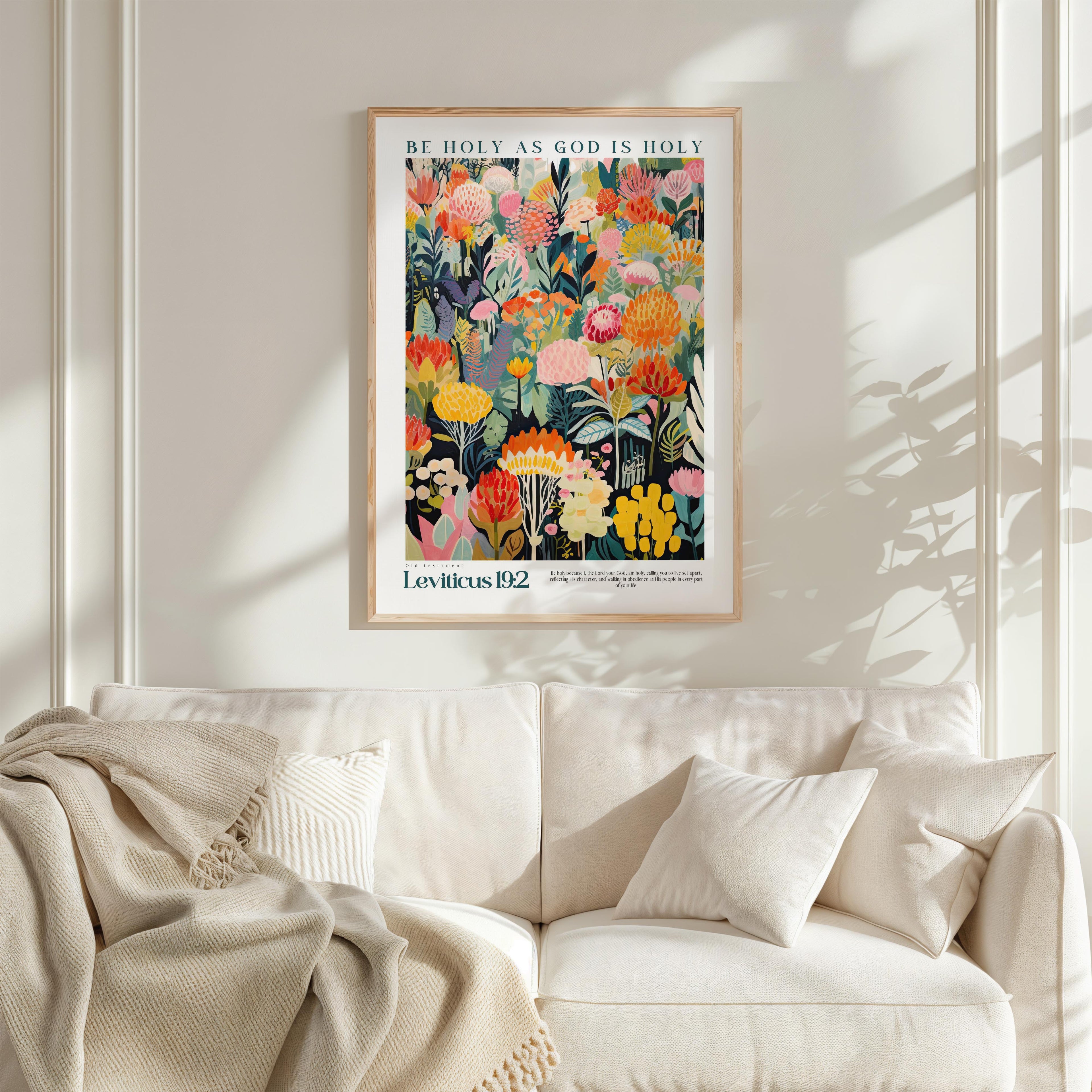 a framed poster of a colorful floral design hanging on a wall above a white couch.