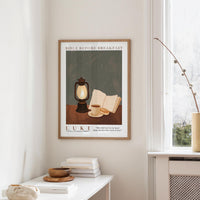 a framed poster of a lantern, a book, and a cup on a table, with a quote from the Bible about breakfast.