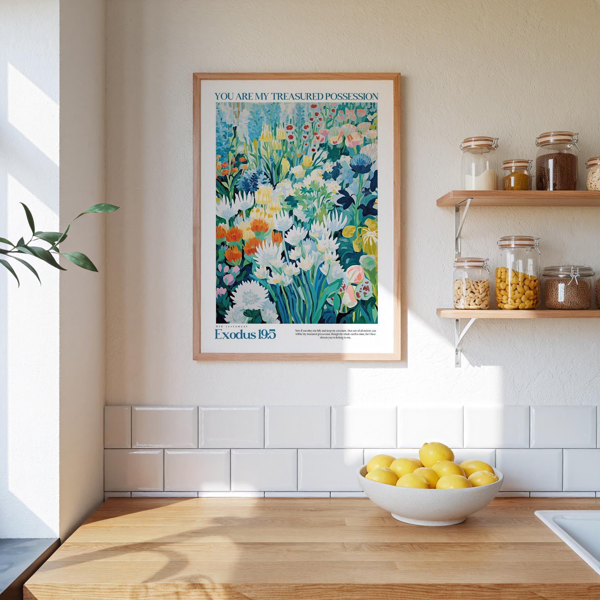 a kitchen scene with a framed poster of a colorful garden hanging on the wall above a wooden countertop with a bowl of lemons.