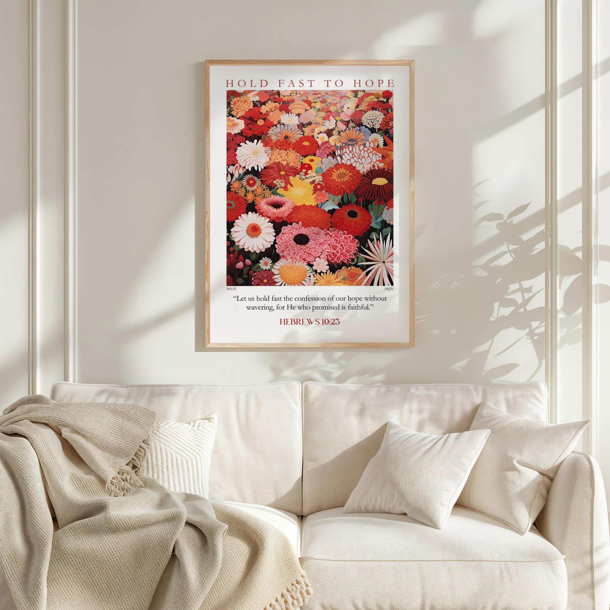 a framed poster of a vibrant floral arrangement hanging on a white wall above a white couch with a blanket draped over it.