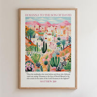The image is a framed poster depicting a colorful illustration of a desert landscape with buildings, palm trees, and other desert flora. The poster is titled "HOSANNA TO THE SON OF DAVID" and includes a biblical verse from Matthew 29.