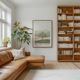 a cozy living room with a large bookshelf filled with books, a comfortable leather couch, and a framed poster of a tree on the wall.