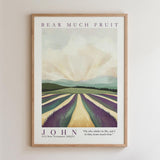 The image is a framed poster featuring a landscape with a field of purple flowers and a mountain range in the background. The poster has a vintage style and is framed in a wooden frame.