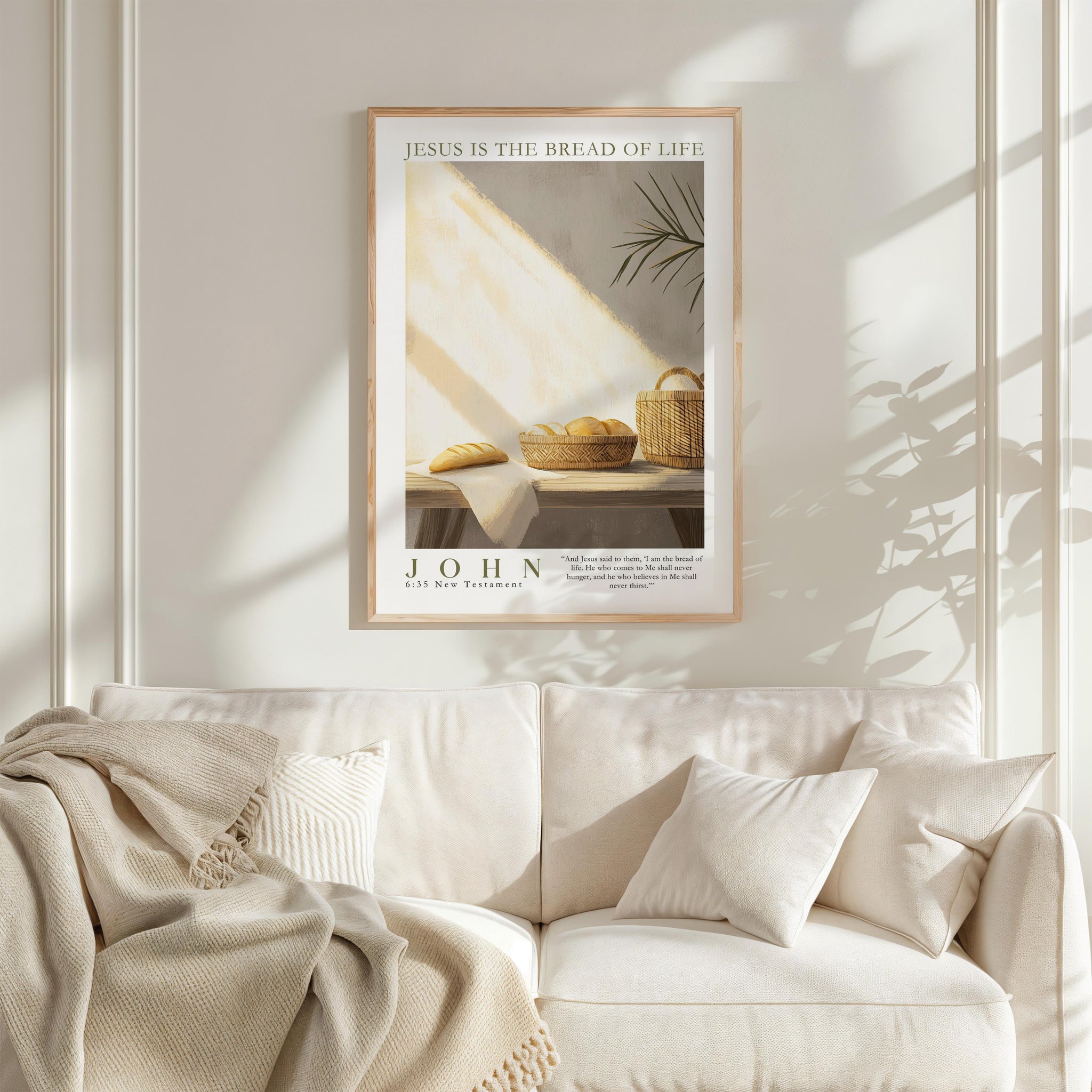 a framed poster of a loaf of bread and a basket of fruit, hanging on a white wall above a white couch with a blanket draped over it.