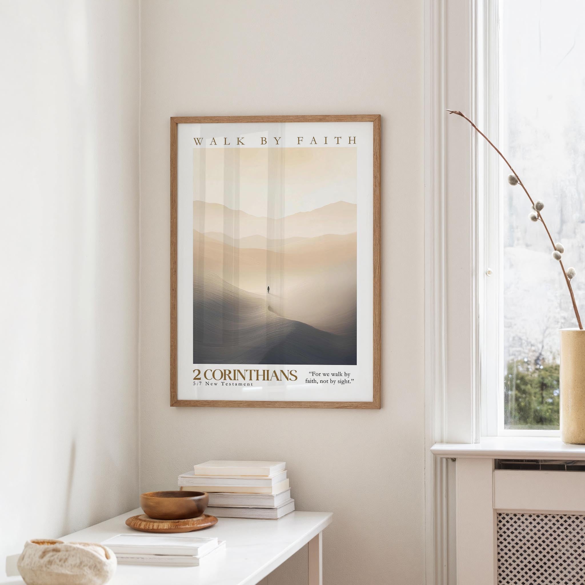 a framed poster of a person walking on a path, with the text "WALK BY FAITH" and "2 CORINTHIANS" below it. The poster is hanging on a wall next to a window, and there is a small table with a stack of books and a bowl on it.