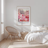 a bedroom with a bed, a wicker chair, and a framed poster of a cityscape with flowers hanging on the wall.