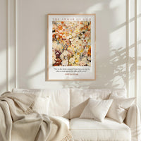a framed poster of a colorful floral painting hanging on a wall above a white couch with a blanket draped over it.