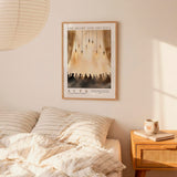 a bedroom setting with a framed poster of a group of people hanging on the wall above a bed with striped bedding.