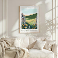 a framed poster of a pastoral scene with a mountain backdrop, hanging on a wall above a white couch with a blanket draped over it.