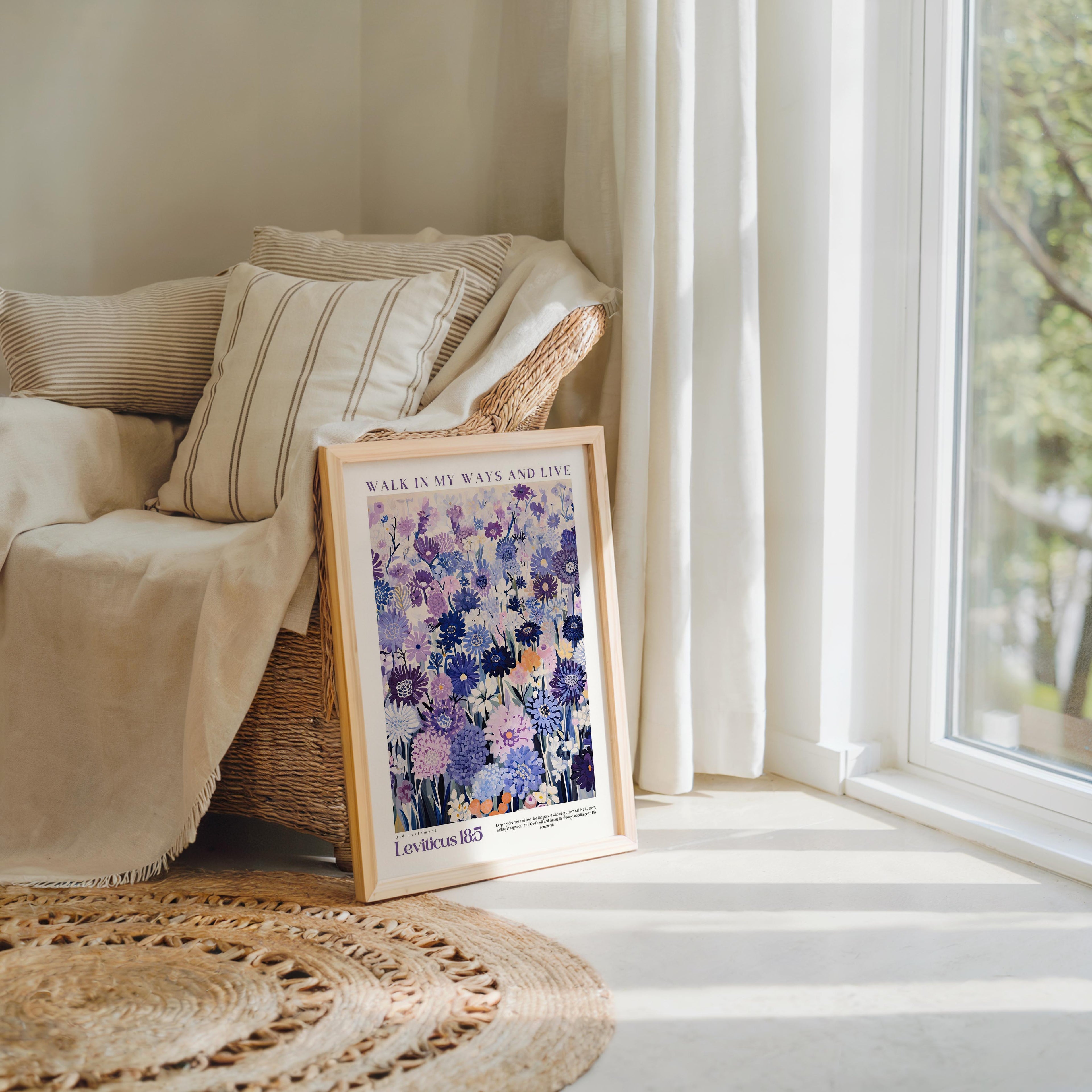 a framed poster of a floral design, placed on a rug in a room with a window and a beige sofa.