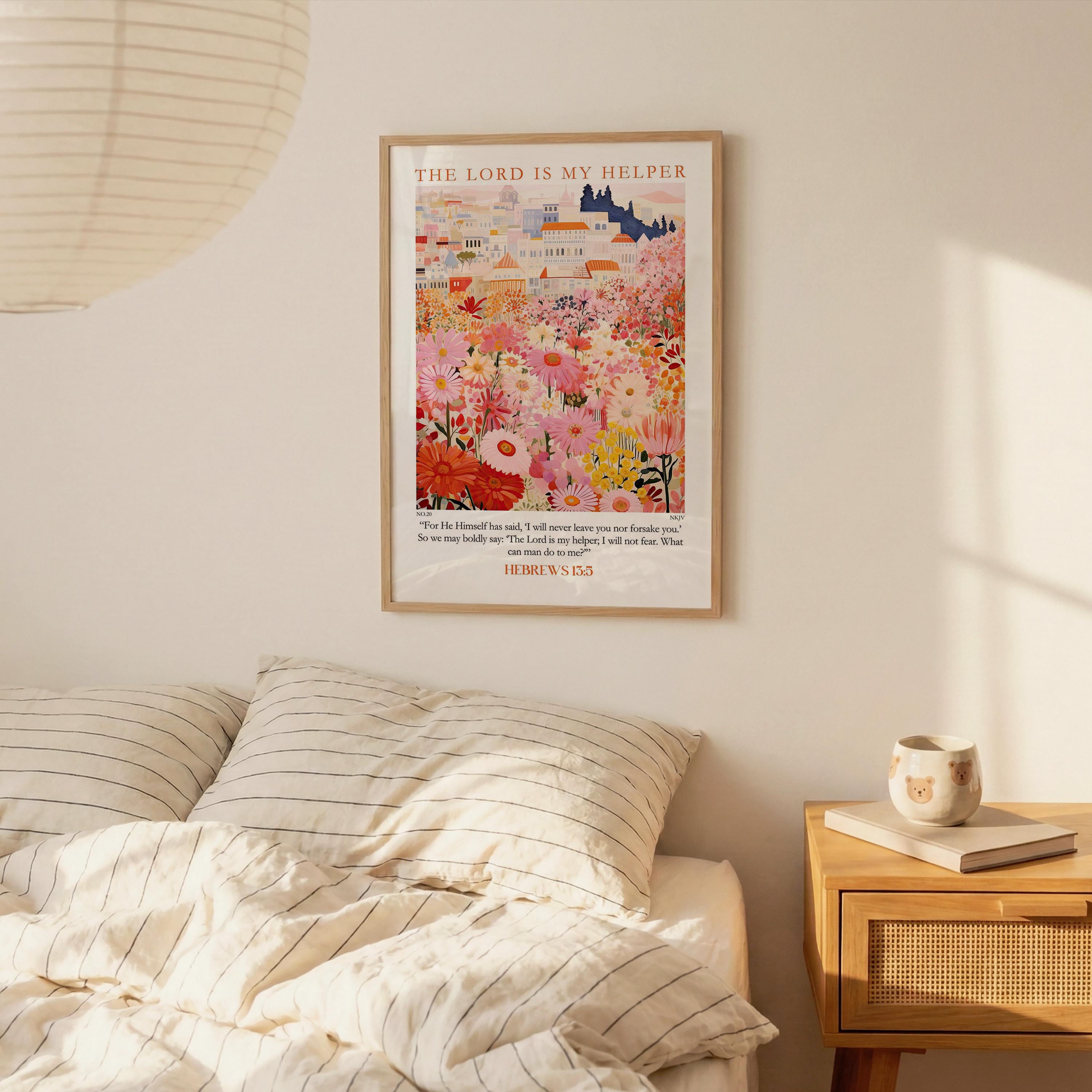 a bedroom scene with a framed poster of a colorful garden hanging on the wall above a bed with striped pillows.