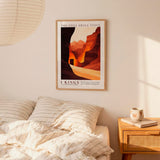 a bedroom scene with a framed poster of a desert landscape hanging on the wall above a bed with striped bedding.