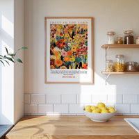 a kitchen scene with a framed poster of a colorful floral design hanging on the wall above a wooden countertop with a bowl of lemons.