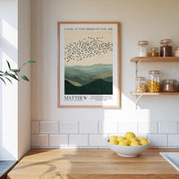 a kitchen scene with a framed poster of a flock of birds above a mountain landscape, a bowl of lemons on a wooden counter, and shelves with jars and containers.