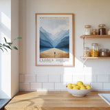 a kitchen scene with a framed poster of a person walking through a desert landscape hanging on the wall above a wooden countertop. On the countertop, there is a bowl of lemons and a plant.