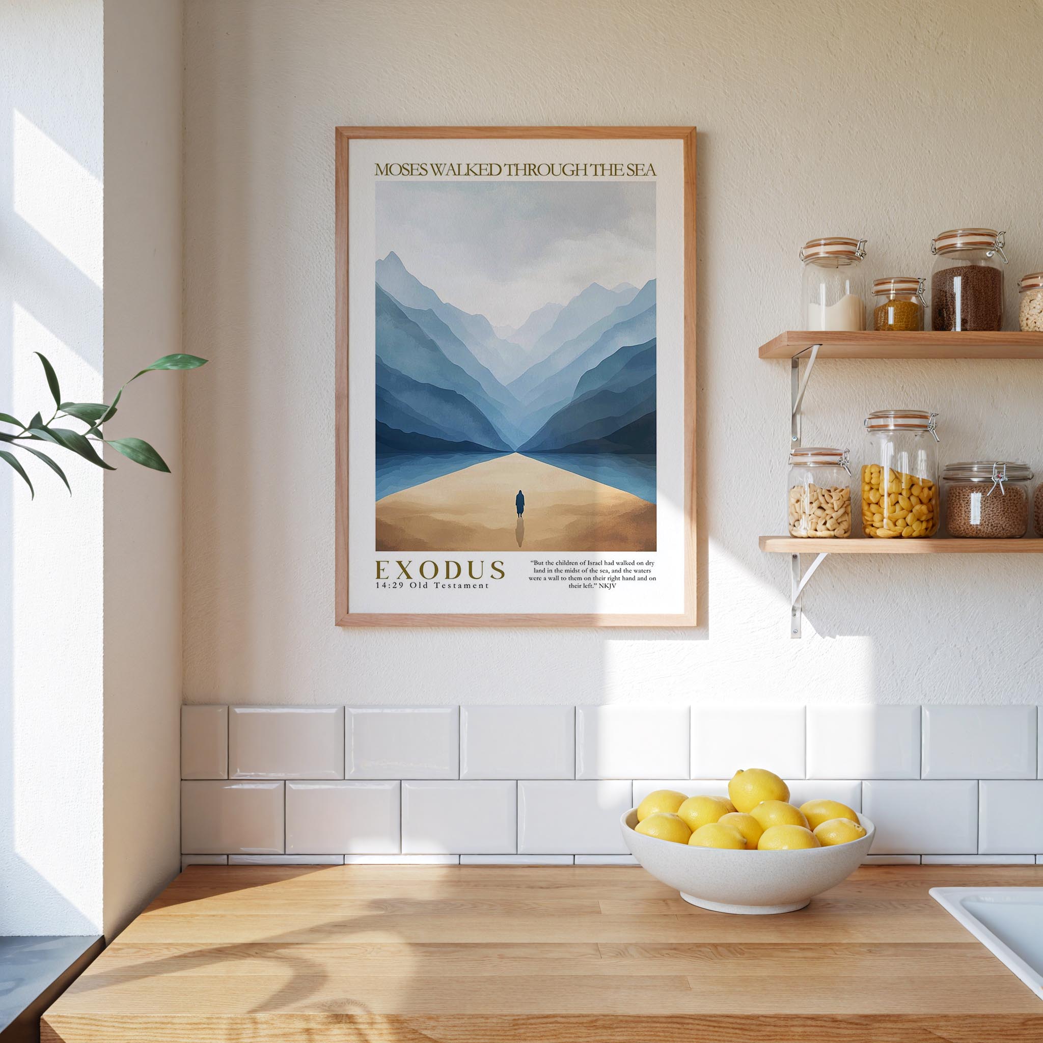 a kitchen scene with a framed poster of a person walking through a desert landscape hanging on the wall above a wooden countertop. On the countertop, there is a bowl of lemons and a plant.