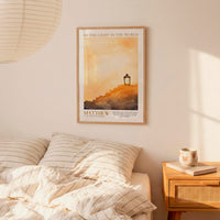 a bedroom scene with a framed poster of a lighthouse on the wall, a bed with striped bedding, and a nightstand with a coffee mug and a book.