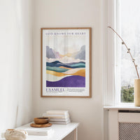 a framed poster of a landscape with mountains and a quote from 1 Samuel, hanging on a wall in a room with a window and a small table with books and a bowl.