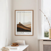 a framed poster of a mountain landscape with the text "BE READY FOR THE SON OF MAN" and "MATTHEW 24:4 NEW TESTAMENT (NIV)" below it, hanging on a wall in a room with a window and a small table with books and a bowl.