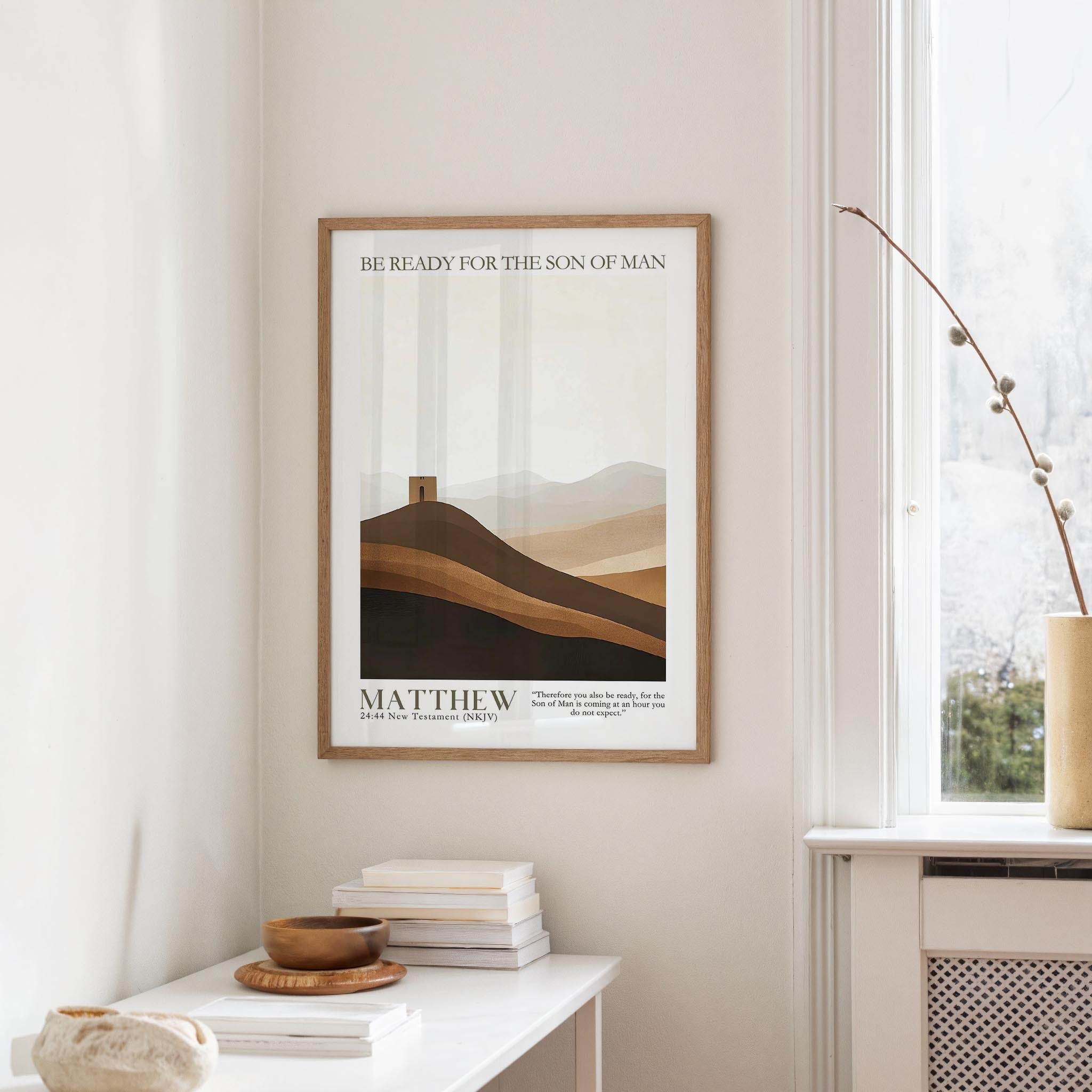 a framed poster of a mountain landscape with the text "BE READY FOR THE SON OF MAN" and "MATTHEW 24:4 NEW TESTAMENT (NIV)" below it, hanging on a wall in a room with a window and a small table with books and a bowl.