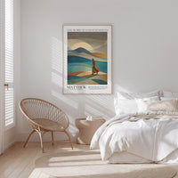 A bedroom with a bed, a woven chair, and a framed poster of a landscape with mountains and a person walking in the distance.