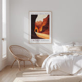 a bedroom with a bed, a woven chair, and a framed poster on the wall.